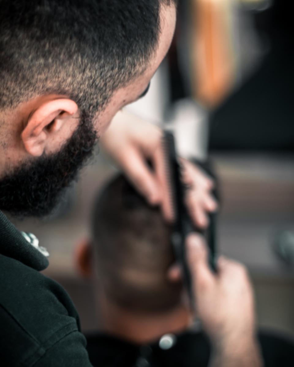 Barber working a fade with clippers and comb